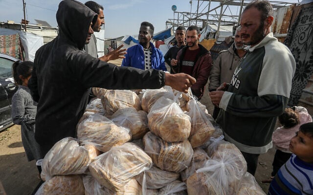Palestinians distribute bread to displaced people in the Mawasi area of Khan Younis, in the southern Gaza Strip, December 8, 2025. (Abed Rahim Khatib/Flash90)