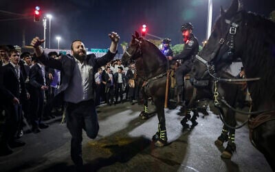 Ultra-Orthodox men block Route 4 during a protest against the jailing of yeshiva students who failed to comply with an IDF draft order, Bnei Brak, December 8, 2025. (David Cohen/Flash90)