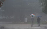 People walk on a foggy, rainy day in Kibbutz Malkia, near the border with Lebanon, on December 10, 2025. (Ayal Margolin/Flash90)