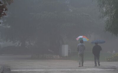 People walk on a foggy, rainy day in Kibbutz Malkia, near the border with Lebanon, on December 10, 2025. (Ayal Margolin/Flash90)