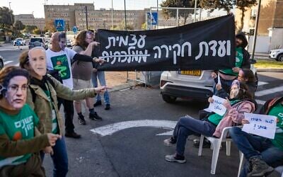 Activists calling for the establishment of a state commission of inquiry into Hamas's October 7, 2023, massacre protest outside the Prime Minister’s Office in Jerusalem, December 22, 2025. (Chaim Goldberg/Flash90)