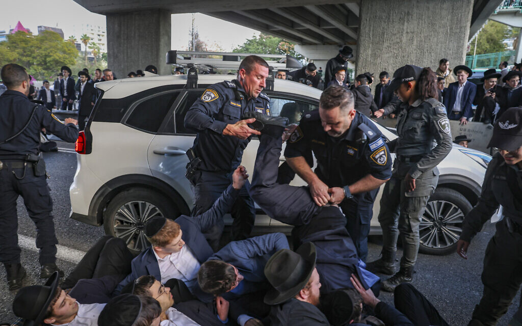 Ultra-Orthodox men scuffle with police during a protest blocking Route 4 in opposition to the jailing of yeshiva students who refused to comply with an army conscription order, near Bnei Brak, December 28, 2025. (David Cohen/Flash90)