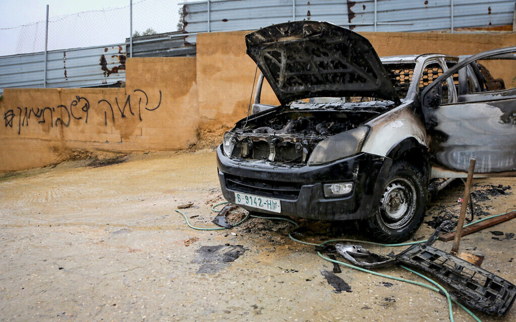 A burnt car is seen next to threatening graffiti in the West Bank town of Huwara, December 28, 2025. (Nasser Ishtayeh/Flash90)