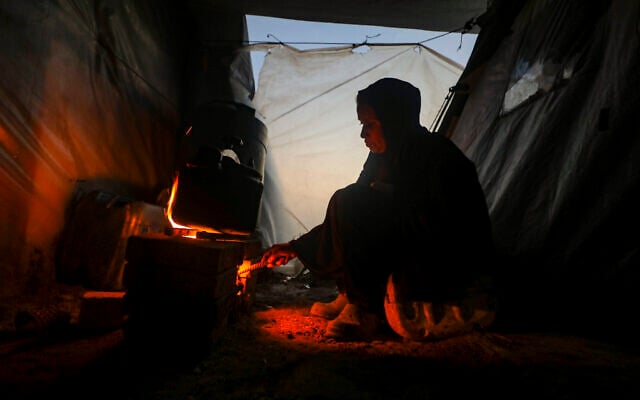 Palestinians warm themselves and cook over a bonfire in the Bureij area in the central Gaza Strip, December 30, 2025. (Ali Hassan/Flash90)