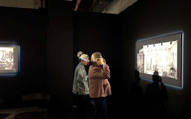 Visitors looking at Maya Zack's artwork from "HaMivne," a pop-up exhibit on display through December 29, 2025. (Jessica Steinberg/Times of Israel)