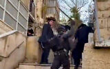 Screen capture from a video of a riot control police officer hitting ultra-Orthodox men with a baton during rioting in Jerusalem, December 18, 2025. (Screen capture: X)