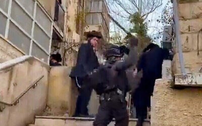 Screen capture from a video of a riot control police officer hitting ultra-Orthodox men with a baton during rioting in Jerusalem, December 18, 2025. (Screen capture: X) Screen capture from a video of a riot control police officer hitting ultra-Orthodox men with a baton during rioting in Jerusalem, December 18, 2025. (Screen capture: X)