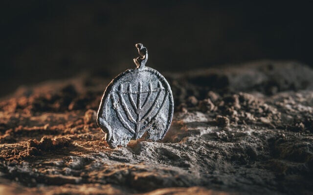 A 1,300-year-old menorah-decorated pendant found at the Davidson Archaeological Park in Jerusalem, in a discovery announced on December 15, 2025. (Eliyahu Yanai/City of David) A 1,300-year-old menorah-decorated pendant found at the Davidson Archaeological Park in Jerusalem, in a discovery announced on December 15, 2025. (Eliyahu Yanai/City of David)