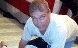 Former UK prince Andrew seen kneeling over an unidentified woman in an undated photo from the Epstein files released January 30, 2026. (US Department of Justice)