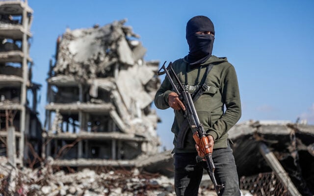 Illustrative: A Hamas operative stands guard as Egyptian workers accompanied by members of the International Committee of the Red Cross (ICRC) use a digger to search for the remains of hostages in the Jabalia refugee camp, in the northern of Gaza Strip, on December 1, 2025. (Omar AL-QATTAA / AFP)