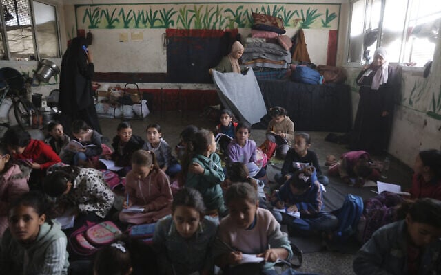 Palestinian children, many of whom are part of displaced families, sit on the floor as they attend class, at the UNRWA Deir al-Balah Joint School, west of Deir al-Balah, in the central Gaza Strip on December 6, 2025. (Photo by BASHAR TALEB / AFP)