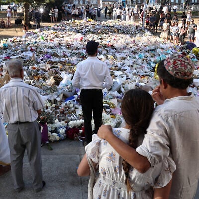 A rabbi (center) delivers a sermon as mourners gather in front of tributes laid in memory of victims of a terror attack on a Hanukkah celebration at Bondi Beach, in Sydney, on December 20, 2025. (David Gray/AFP)
