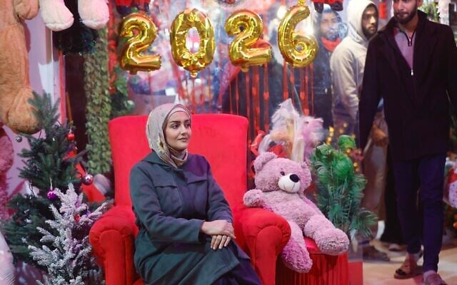 A Palestinian woman sits amid New Year's decorations in Gaza City on December 31, 2025. (Omar Al-Qattaa/AFP) A Palestinian woman sits amid New Year's decorations in Gaza City on December 31, 2025. (Omar Al-Qattaa/AFP)