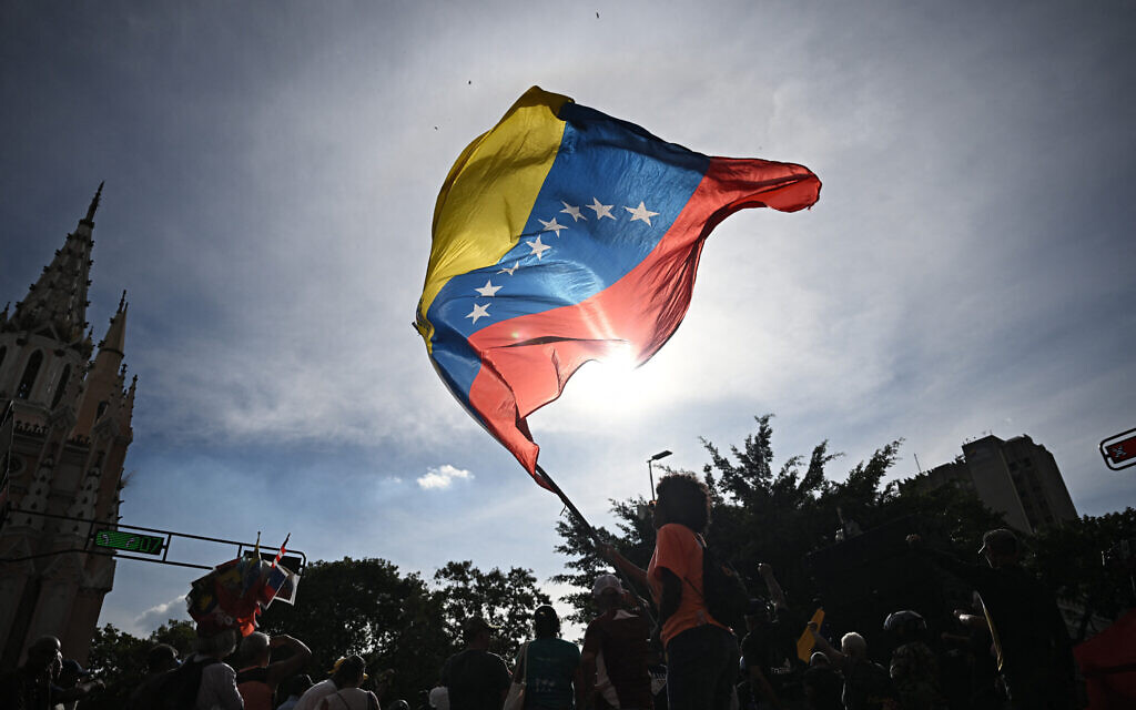 A person flies a national flag in Caracas, Venezuela, on January 3, 2026, after US forces captured Venezuelan leader Nicolas Maduro. (Federico PARRA / AFP) A person flies a national flag in Caracas, Venezuela, on January 3, 2026, after US forces captured Venezuelan leader Nicolas Maduro. (Federico PARRA / AFP)