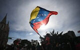 A person flies a national flag in Caracas, Venezuela, on January 3, 2026, after US forces captured Venezuelan leader Nicolas Maduro. (Federico PARRA / AFP)