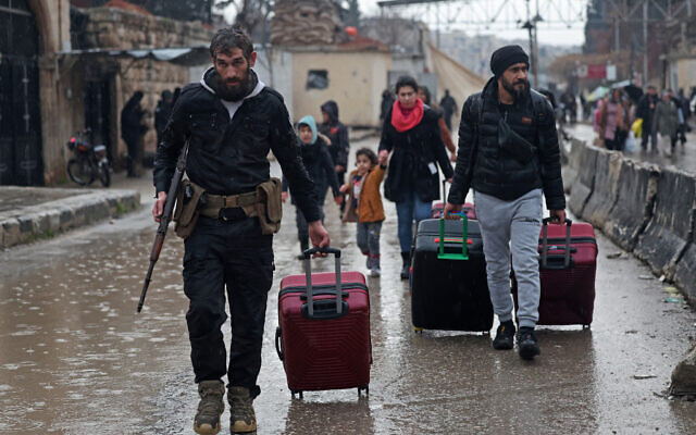 Residents of Aleppo's Sheikh Maqsoud area evacuate their neighborhood after warnings from the Syrian army that called on civilians to get out of harms way, following the refusal of Kurdish fighter forces to leave Aleppo, on January 9, 2026. (OMAR HAJ KADOUR / AFP)
