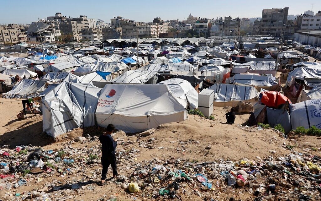 A child walks past garbage towards tent shelters housing displaced Palestinian families that are set up on empty land in Gaza City on January 11, 2026. (Omar AL-QATTAA / AFP)