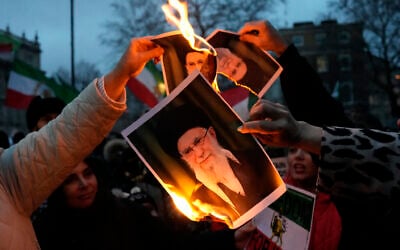 Protesters burn images of Ayatollah Ali Khamenei during a rally in support of anti-regime protesters in Iran, in central London, January 11, 2026. (Carlos Jasso/AFP)