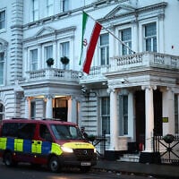 A police van waits outside the Iranian Embassy, flying the flag of the Islamic Republic of Iran, central London, January 12, 2026. (HENRY NICHOLLS / AFP)
