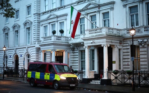 A police van waits outside the Iranian Embassy, flying the flag of the Islamic Republic of Iran, central London, January 12, 2026. (HENRY NICHOLLS / AFP)