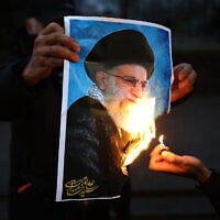Anti-Iranian regime protesters burn an image of Ayatollah Ali Khamenei, during a gathering outside the Iranian Embassy, central London, on January 12, 2026. (Henry Nicholls/AFP)