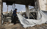 A Palestinian man fixes a tent shelter at a war-damaged building, parts of which collapsed on a windy winter day in Gaza City on January 13, 2026. (Photo by Omar AL-QATTAA / AFP)