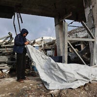 A Palestinian man fixes a tent shelter at a war-damaged building, parts of which collapsed on a windy winter day in Gaza City on January 13, 2026. (Photo by Omar AL-QATTAA / AFP)