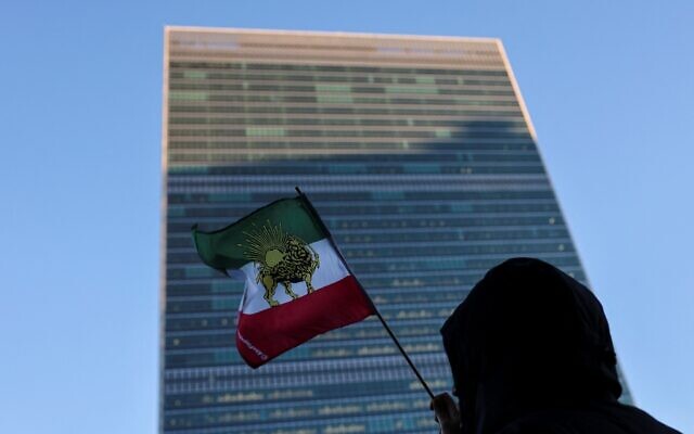 A protester waves the pre-Islamic Revolution Iranian flag outside UN headquarters, during a United Nations Security Council meeting on Iran, in New York on January 15, 2026. (Angela Weiss/AFP)