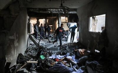Palestinian men maneuver past debris and broken furniture, after an Israeli strike on the family home of Hamas military commander Muhammad al-Hawli, west of Deir al-Balah, in the central Gaza Strip on January 16, 2026.  (Basahr Taleb/AFP)