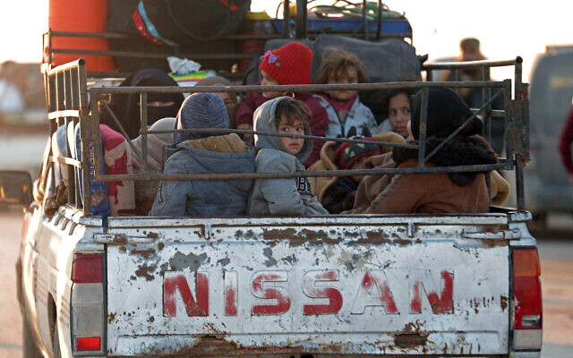 People sit in a vehicle along with their belongings as they flee from the vicinity of the Humaymah village, east of Aleppo city, Syria, on January 16, 2026. (OMAR HAJ KADOUR / AFP)