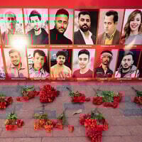 Flowers are placed next to a display with photos of Iraninan people killed during the recent protests in Iran, during a rally and vigil in their honor by Iranian Americans, outside the White House in Washington, January 16, 2026. (Saul Loeb/AFP)