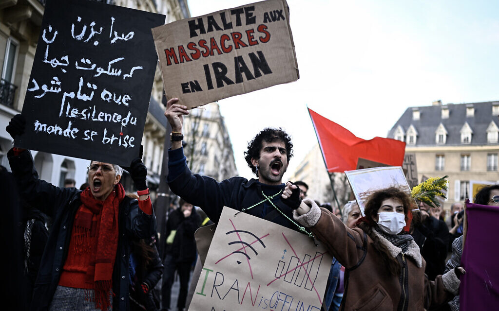 A protester holds a placard reading "Stop the massacres in Iran" during a rally in support of the Iranian people in Paris on January 17, 2026.  (Photo by JULIEN DE ROSA / AFP)
