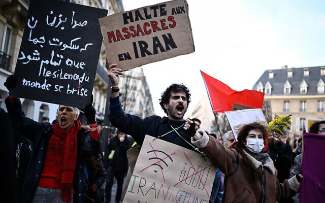 A protester holds a placard reading "Stop the massacres in Iran" during a rally in support of the Iranian people in Paris on January 17, 2026.  (Photo by JULIEN DE ROSA / AFP)