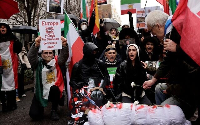 A man holds a banner reading 'Europe deaf, blind, mute in front of Iran People genocide'  as protestors gather during a demonstration in support of Iranian People in Madrid on January 17, 2026.  (Photo by Oscar DEL POZO / AFP)