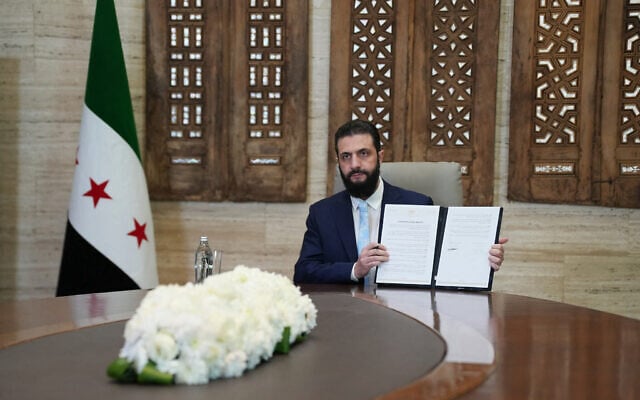 Syria's President Ahmed al-Sharaa signs an agreement with the chief of the Kurdish-led Syrian Democratic Forces at the Presidential Palace in Damascus on January 18, 2026. (Rami al SAYED / AFP)