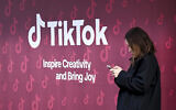 A woman uses her phone in front of TikTok's booth during the World Economic Forum (WEF) annual meeting in Davos on January 19, 2026. (Ina Fassbender / AFP)
