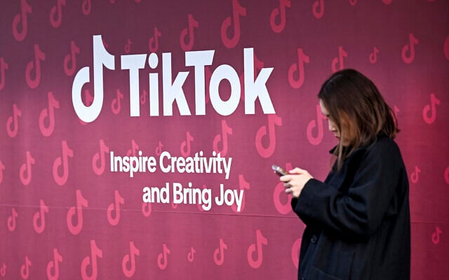 A woman uses her phone in front of TikTok's booth during the World Economic Forum (WEF) annual meeting in Davos on January 19, 2026. (Ina Fassbender / AFP) A woman uses her phone in front of TikTok's booth during the World Economic Forum (WEF) annual meeting in Davos on January 19, 2026. (Ina Fassbender / AFP)
