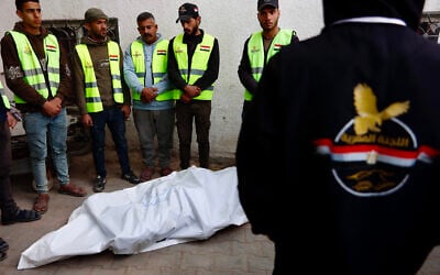 Palestinian employees working for the Egyptian Committee for Gaza Relief gather around a body bag carrying two bodies at Nasser Hospital in Gaza City on January 21, 2026. (Omar AL-QATTAA / AFP)