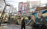 An Iranian woman walks past an anti-US and anti-Israel banner hanging on a building in Palestine Square in Tehran on January 27, 2026 (ATTA KENARE / AFP)