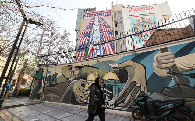 An Iranian woman walks past an anti-US and anti-Israel banner hanging on a building in Palestine Square in Tehran on January 27, 2026 (ATTA KENARE / AFP) An Iranian woman walks past an anti-US and anti-Israel banner hanging on a building in Palestine Square in Tehran on January 27, 2026 (ATTA KENARE / AFP)