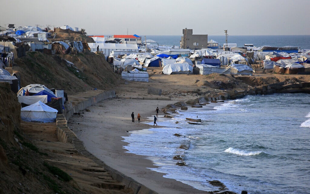 People stand near tents housing displaced Palestinians in the al-Mawasi area of Khan Younis, in the southern Gaza Strip on January 30, 2026. (Bashar Taleb/AFP)