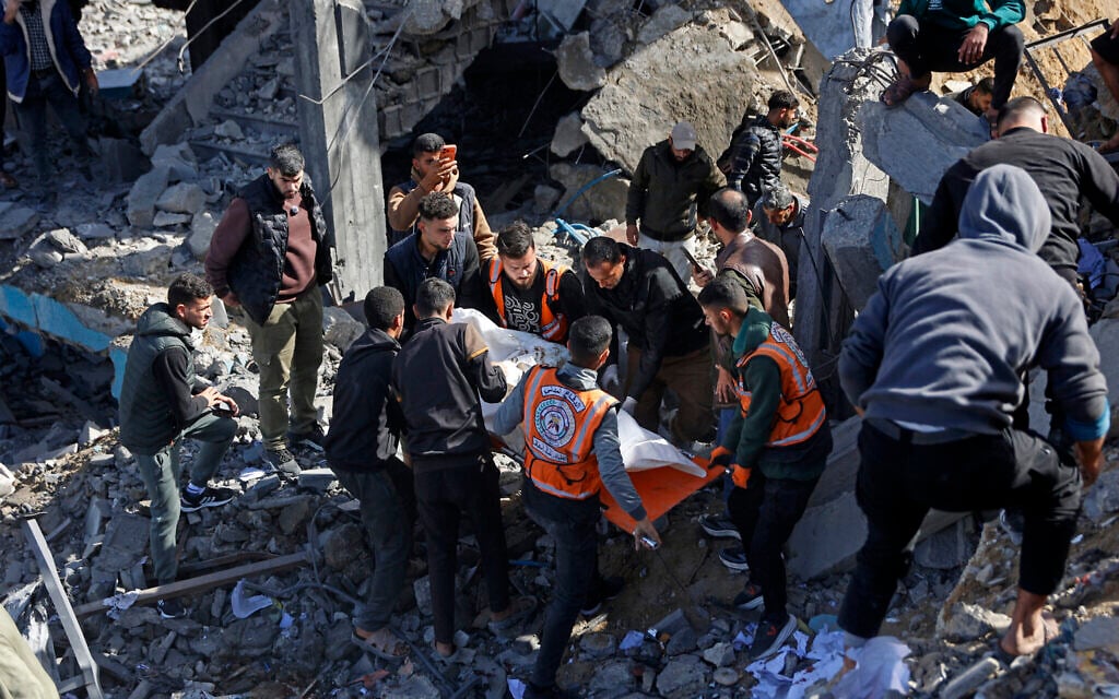 Rescuers carry the body of someone killed in an Israeli airstrike, amid the debris of Sheikh Radwan police station in Gaza City on January 31, 2026. (Omar AL-QATTAA / AFP)