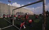 Palestinian girls take part in a soccer practice session at a pitch next to Israel's security barrier in Aida refugee camp, in the West Bank city of Bethlehem, December 26, 2025. (AP Photo/Mahmoud Illean)
