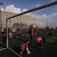 Palestinian girls take part in a soccer practice session at a pitch next to Israel's security barrier in Aida refugee camp, in the West Bank city of Bethlehem, December 26, 2025. (AP Photo/Mahmoud Illean)
