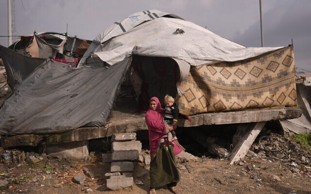 A woman holds a child as they stand in front of their tent in a makeshift camp for displaced Palestinians set up in an area in Gaza City, December 29, 2025. (AP/Jehad Alshrafi) A woman holds a child as they stand in front of their tent in a makeshift camp for displaced Palestinians set up in an area in Gaza City, December 29, 2025. (AP/Jehad Alshrafi)