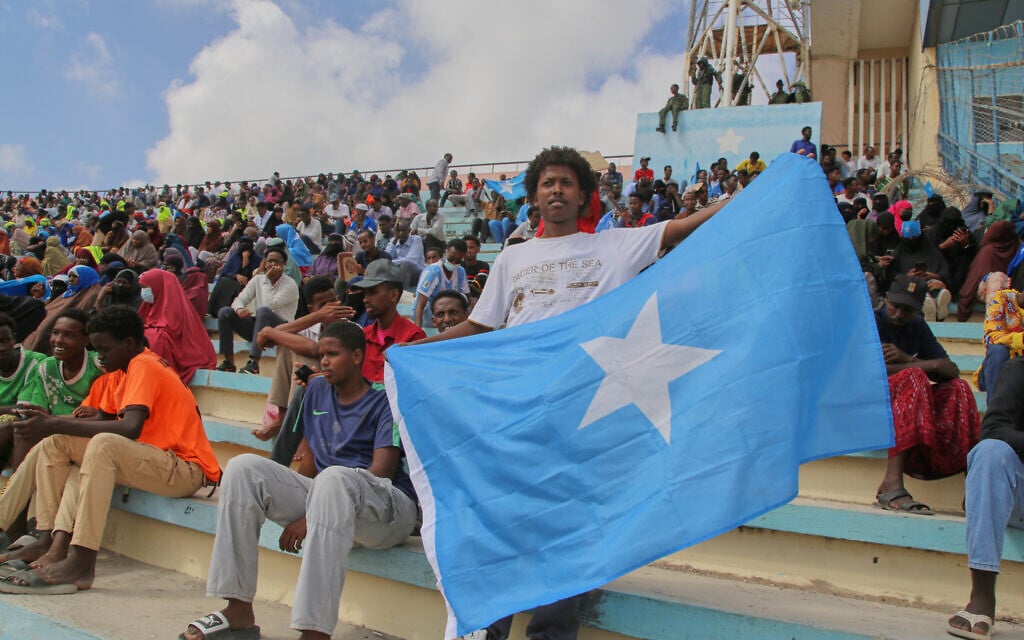 A man holds the flag of Somalia as people gather at the Mogadishu stadium while they protest Israel's recognition of the breakaway region of Somaliland as an independent nation, in Mogadishu, Somalia, December 30, 2025. (AP/Farah Abdi Warsameh)