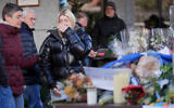 People bring flowers near the sealed off Le Constellation bar, where a devastating fire left dead and injured during the New Year's celebrations in Crans-Montana, Swiss Alps, Switzerland, Jan. 2, 2026. (AP Photo/ Antonio Calanni)
