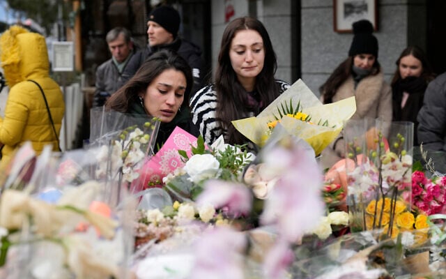 Two women lay flowers near the sealed off Le Constellation bar in Crans-Montana, Swiss Alps, Switzerland, Jan. 2, 2026, where a devastating fire left dead and injured during the New Year's celebrations. (AP Photo/Baz Ratner)