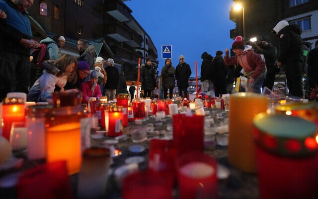 People light candles near the sealed-off Le Constellation bar in Crans-Montana, Switzerland, January 2, 2026, where a devastating fire left 40 people dead and 116 injured during New Year's celebrations. (AP/ Antonio Calanni)