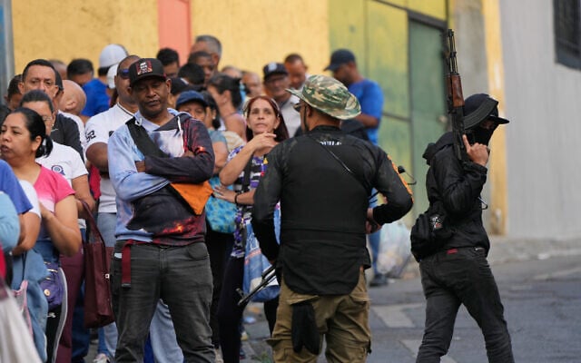 Pro-government armed civilians monitor shoppers lining up outside a supermarket in Caracas, Venezuela, Sunday, January 4, 2026. (AP/Ariana Cubillos)